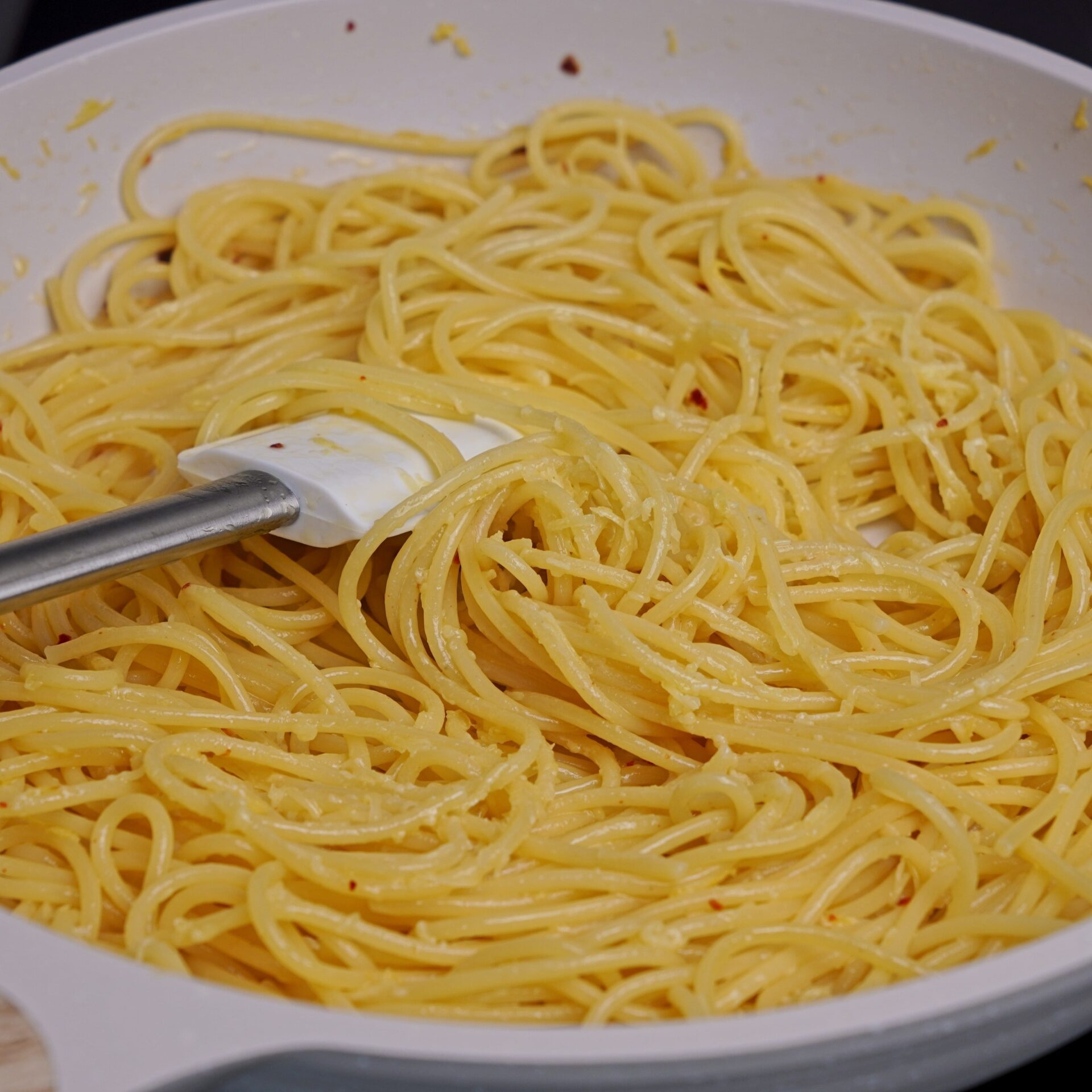 Combining pasta, cheese, lemon juice, and pasta water to bring the sauce together.