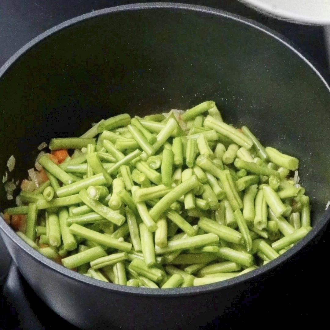 Adding green beans to the pot.