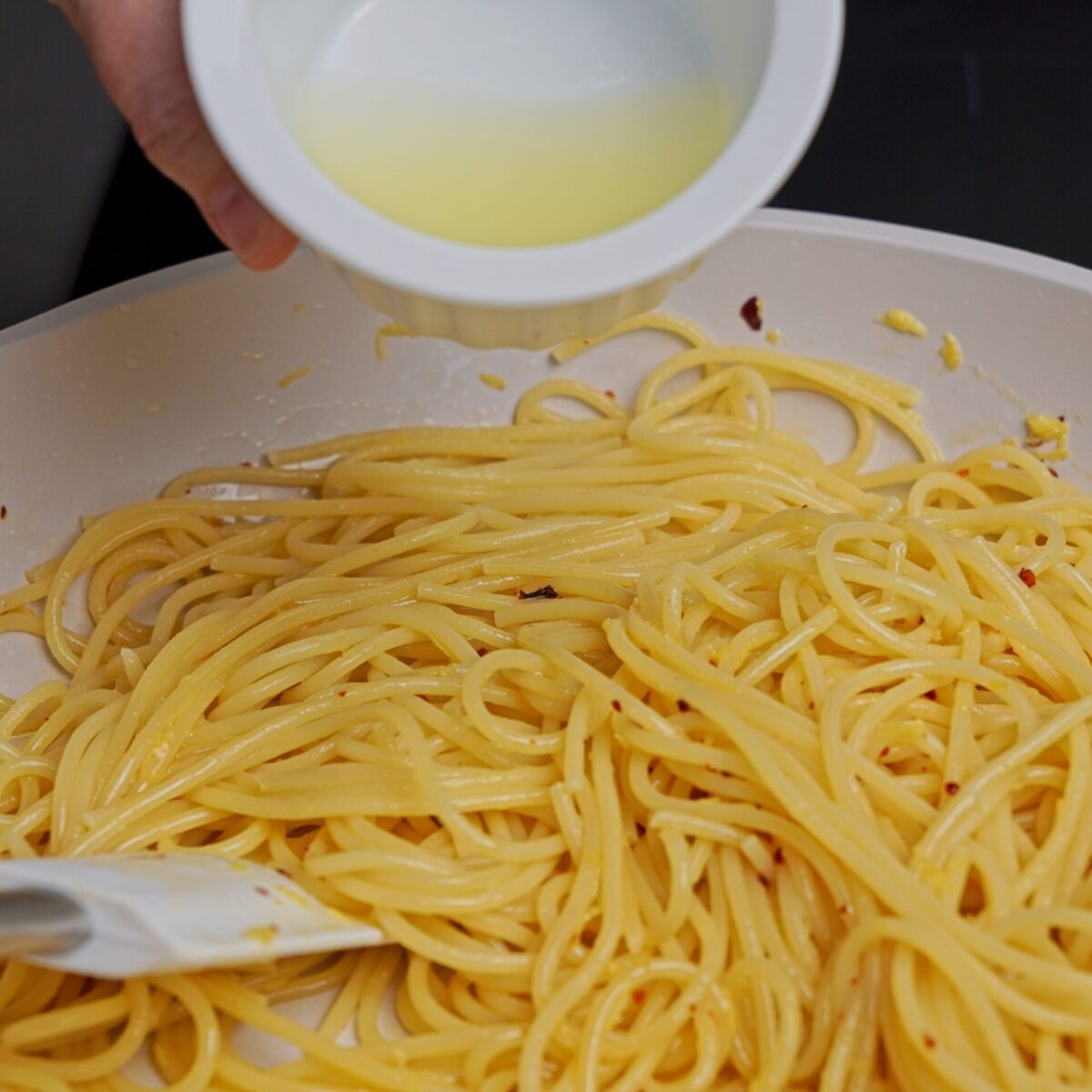 Pouring lemon juice into the pan to enhance the lemon butter sauce.