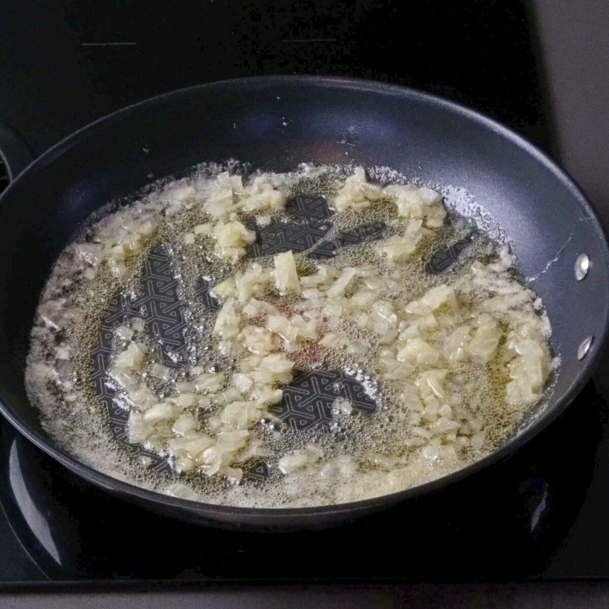 Stirring chopped onion in a pan with oil and butter.