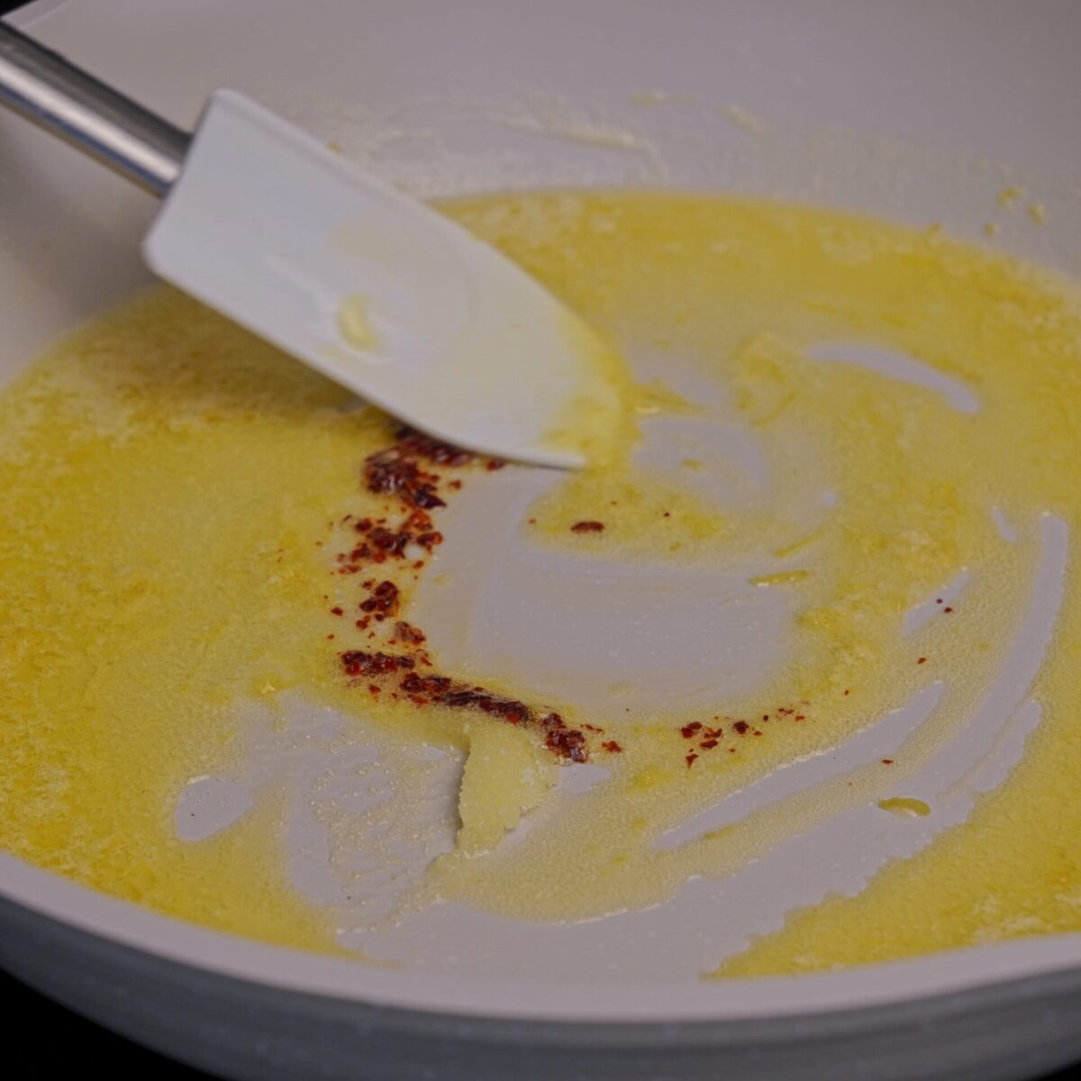 Stirring spices into melted butter in a pan.