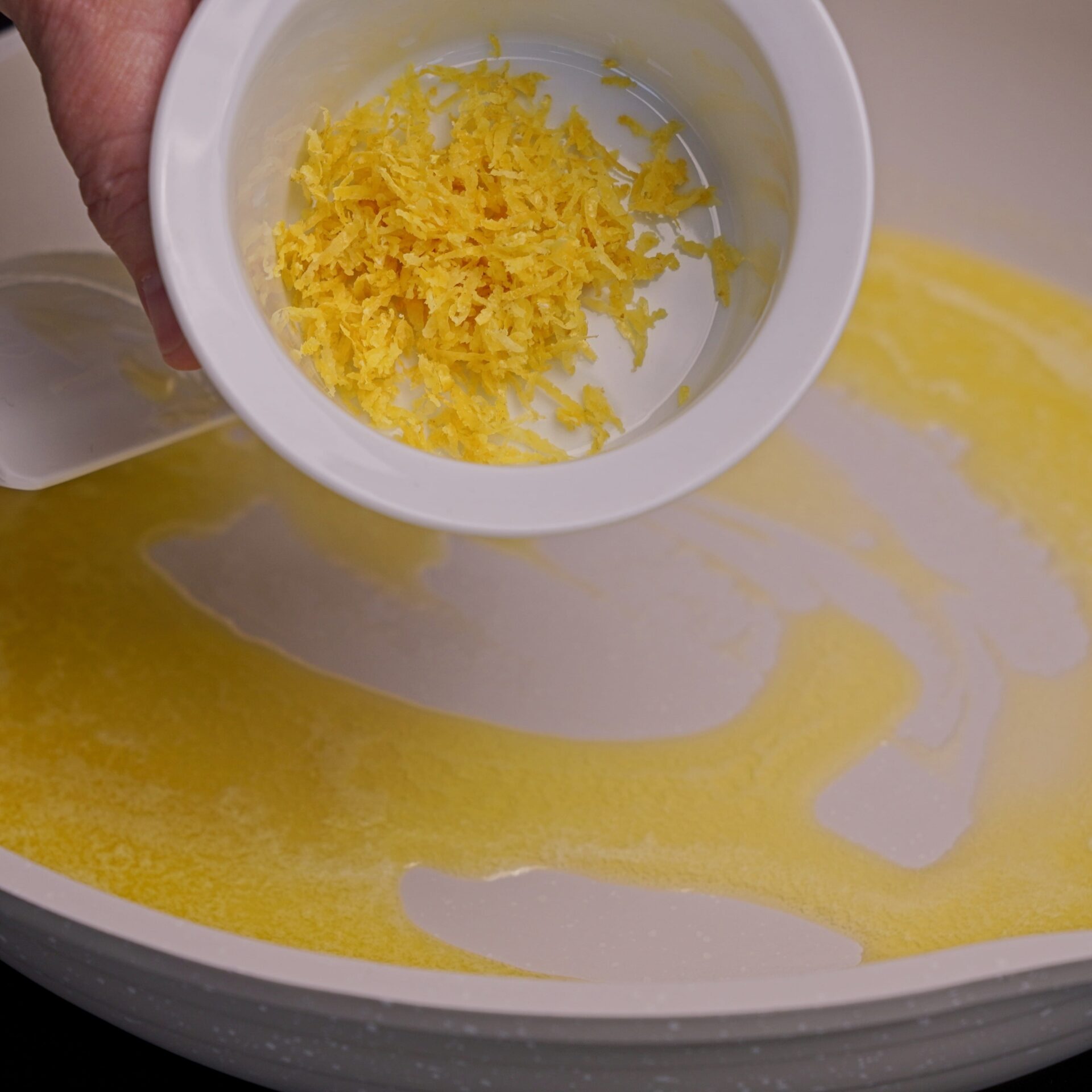 Adding lemon zest to melted butter in a pan.