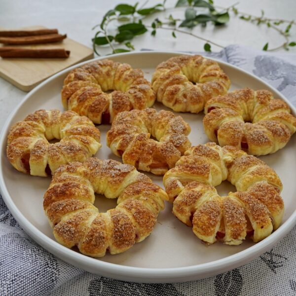 Close-up of delicious apple and puff pastry dessert served on a plate, featuring crispy round puff pastry rings.