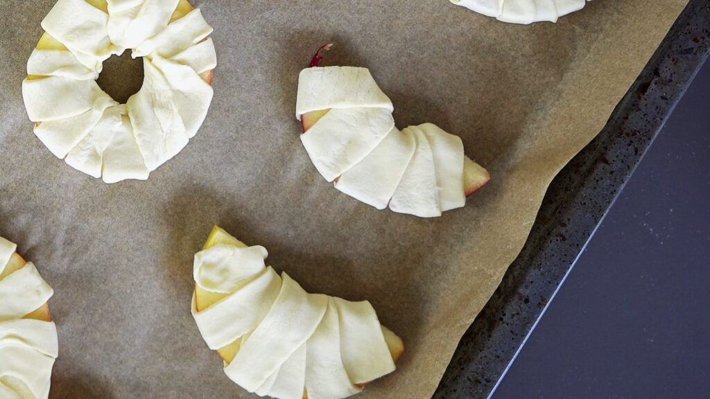Showing puff pastry croissants and puff pastry apple rings on baking form.
