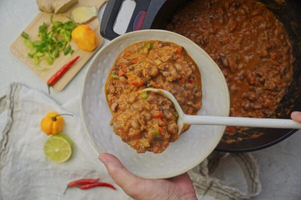 Pouring creamy black-eyed pea soup into a bowl with a ladle.