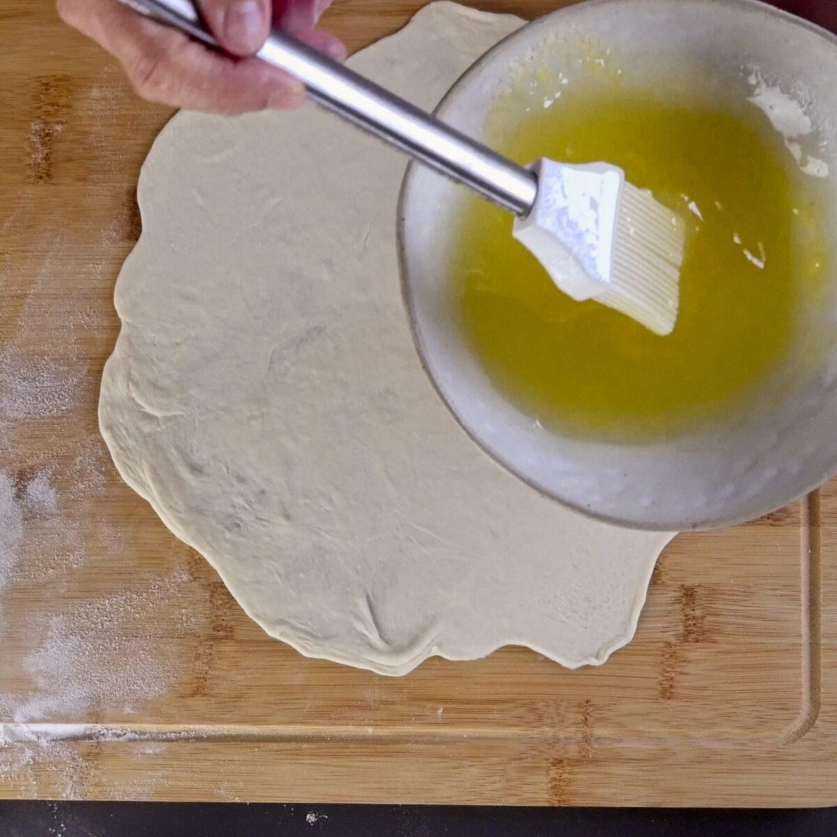 Brushing the dough with a mixture of oil and butter for extra flakiness.
