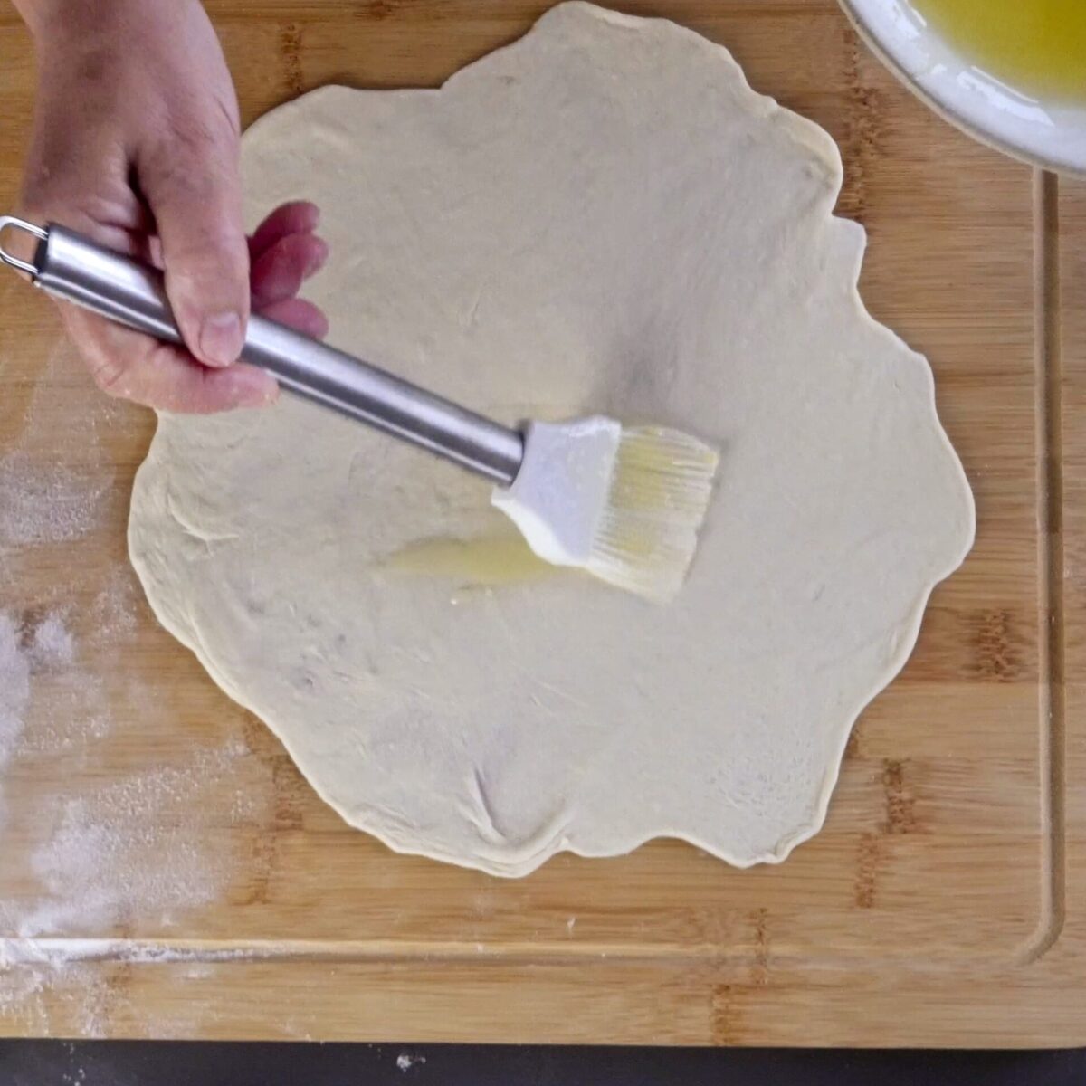 Brushing the dough with oil and butter for a soft, flaky texture.