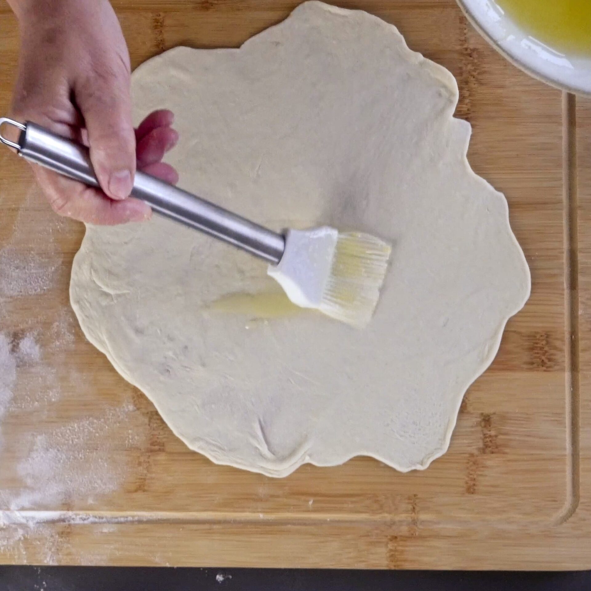 Brushing the dough with oil and butter for a soft, flaky texture.