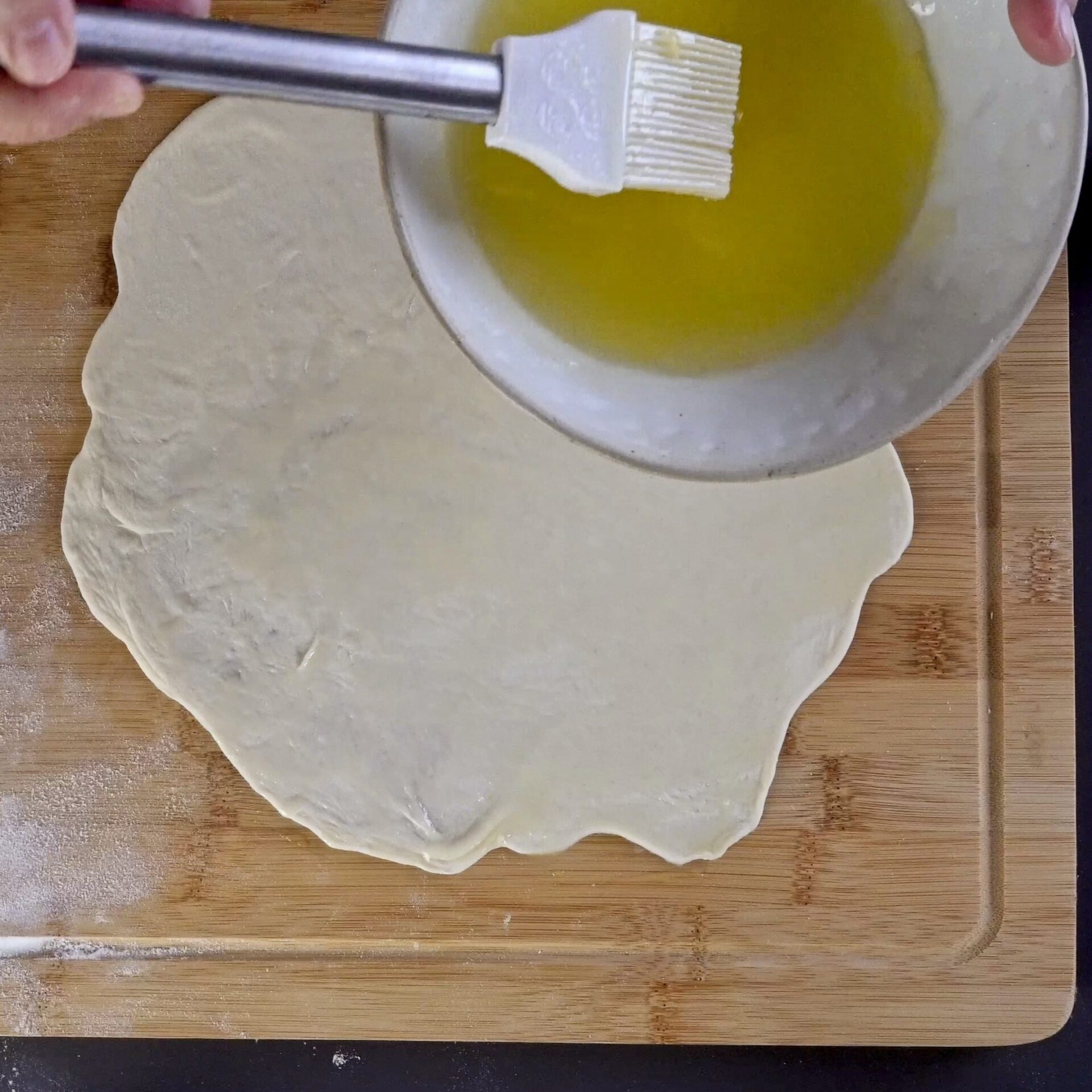 Spreading the oil and butter mixture evenly over the dough.