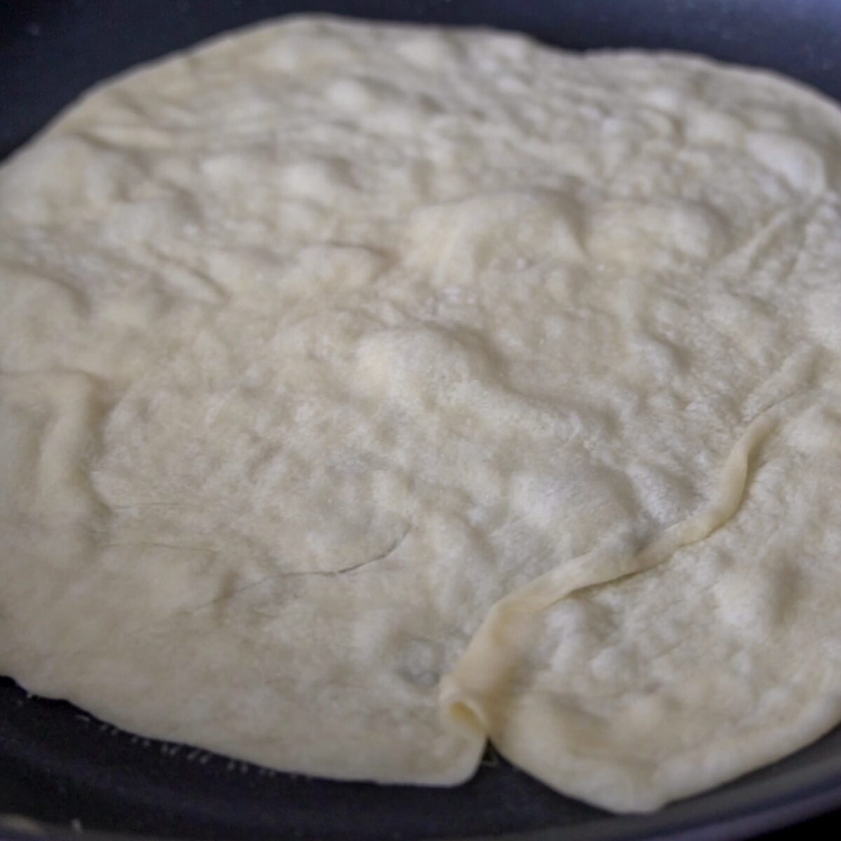 Bubbles forming on the roti as it cooks.