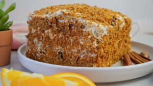 Carrot cake with cream cheese, covered in crumbs, ready to eat.