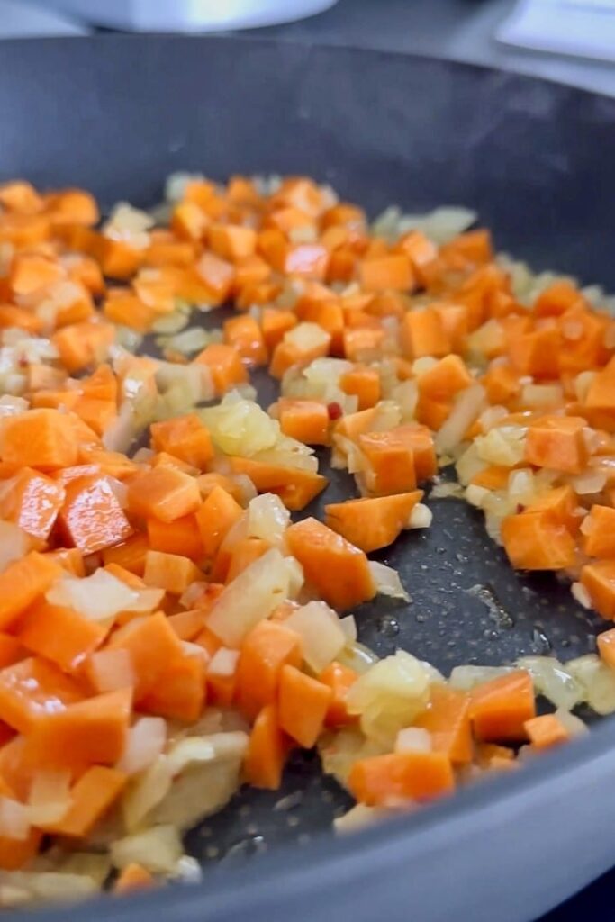 Frying carrots and onions in a pan.