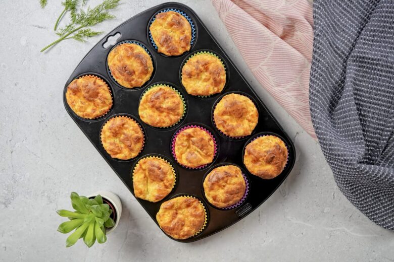 Cheesy muffins recipe with cheddar and eggs. Muffins are in the molds. They look very crispy and cheesy.