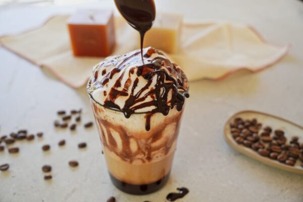 Homemade chocolate syrup drizzled over frothed latte.