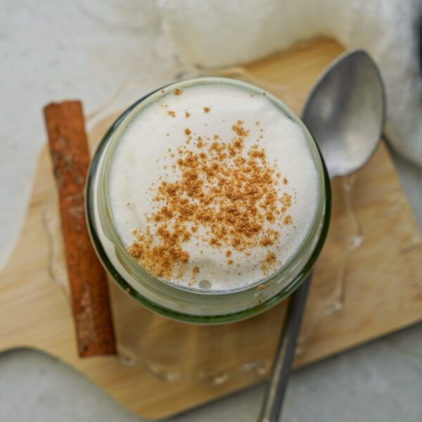 Cinnamon-infused milk in a jar with ground cinnamon sprinkled on top.