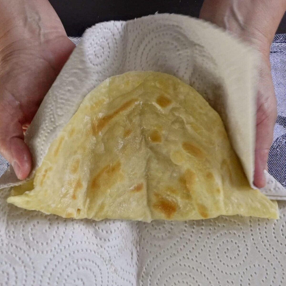 Clapping the roti with your hands to separate the layers.