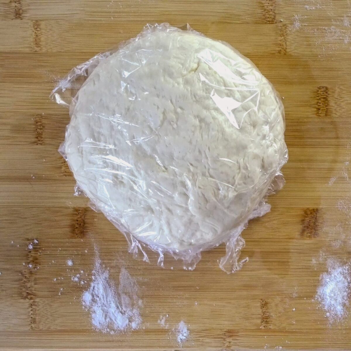 Covering the dough with plastic wrap to rest and soften.