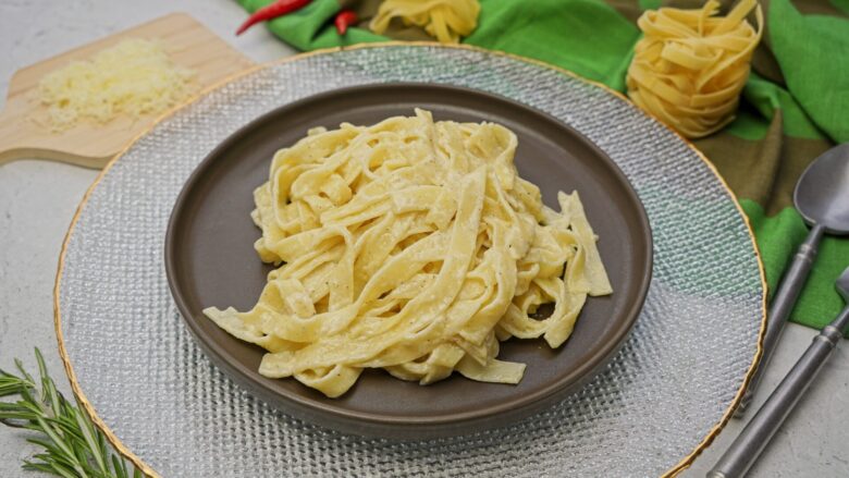 Cream sauce pasta plated on a dark dish, freshly served.