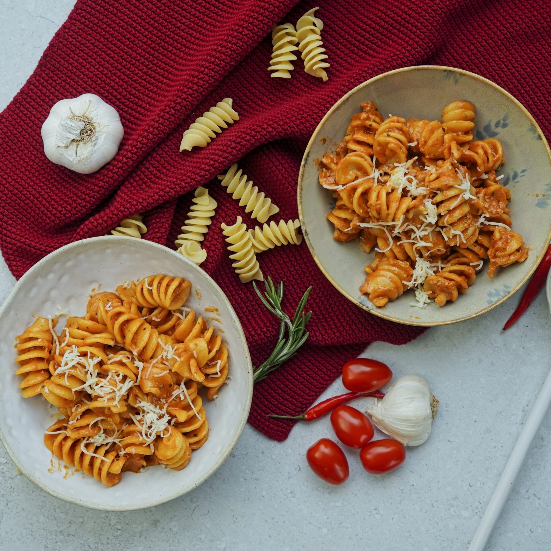 Two bowls of creamy tomato pasta, finished with a sprinkle of freshly grated cheese.