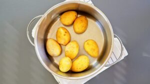 Adding small potatoes to the pot to prepare them to cook.
