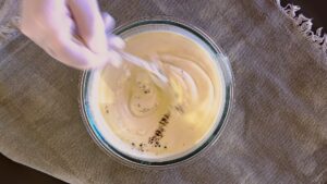 Mixing ingredients for the dressing in a glass bowl: yogurt, mayo, mustard, pepper and salt.
