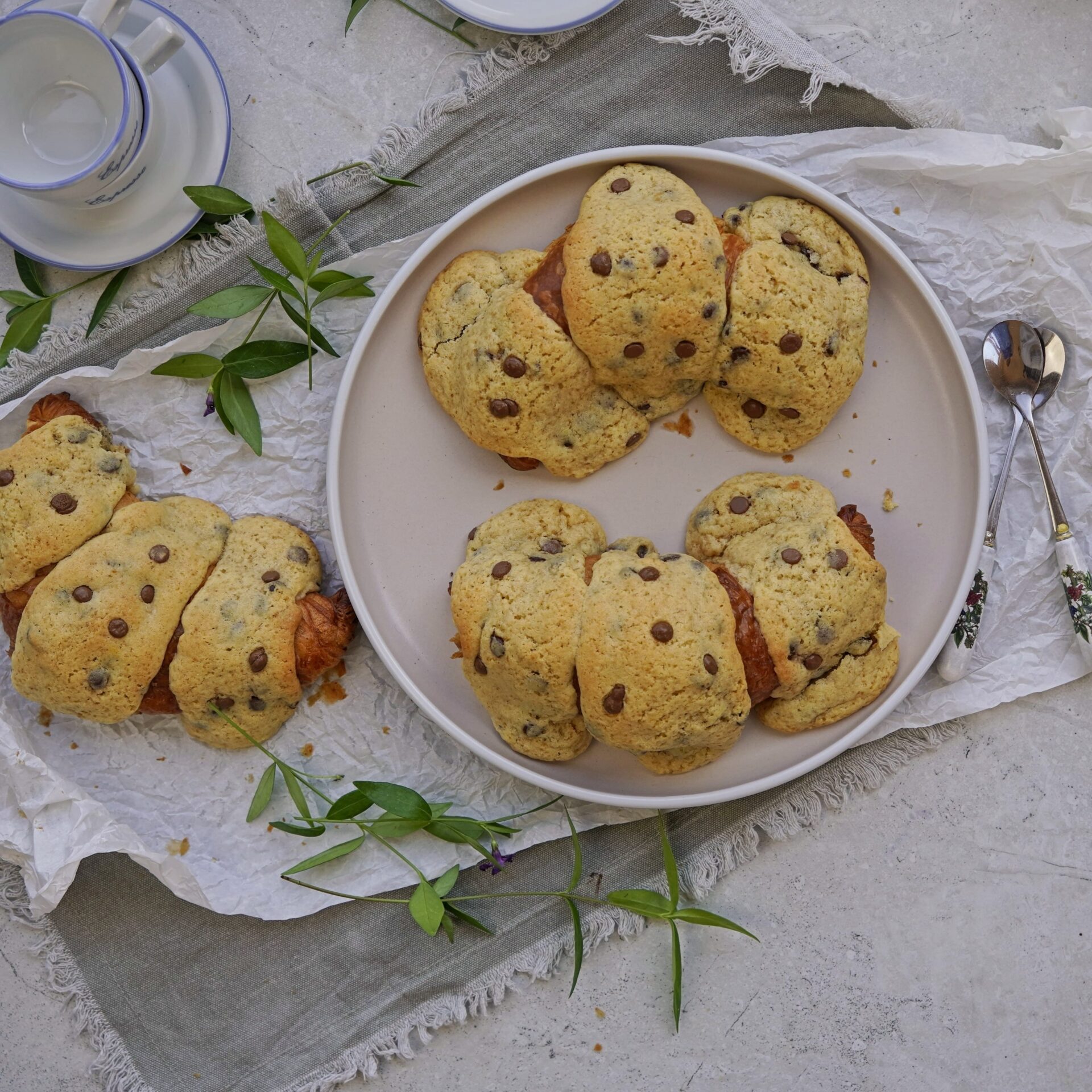 Three croissants with crispy cookie dough topping on a decorated table, viewed from above.