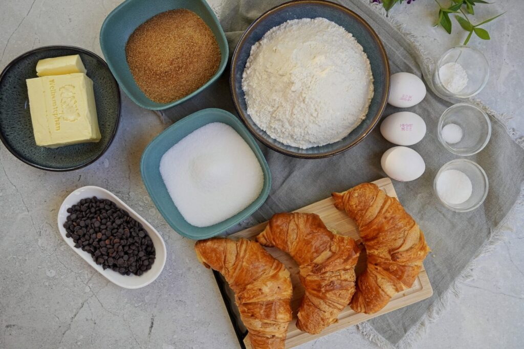 Ingredients for viral crookie on the table: croissants, eggs, brown and white sugar, vanilla sugar, butter, chocolate chips, baking powder, and a pinch of salt.