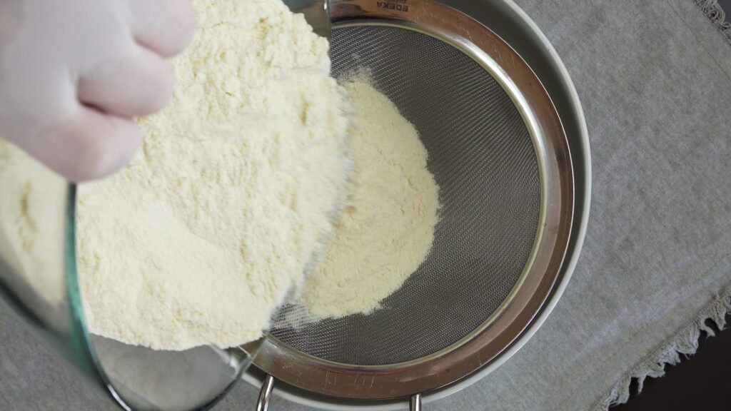 Sifting flour to prepare cookie dough.