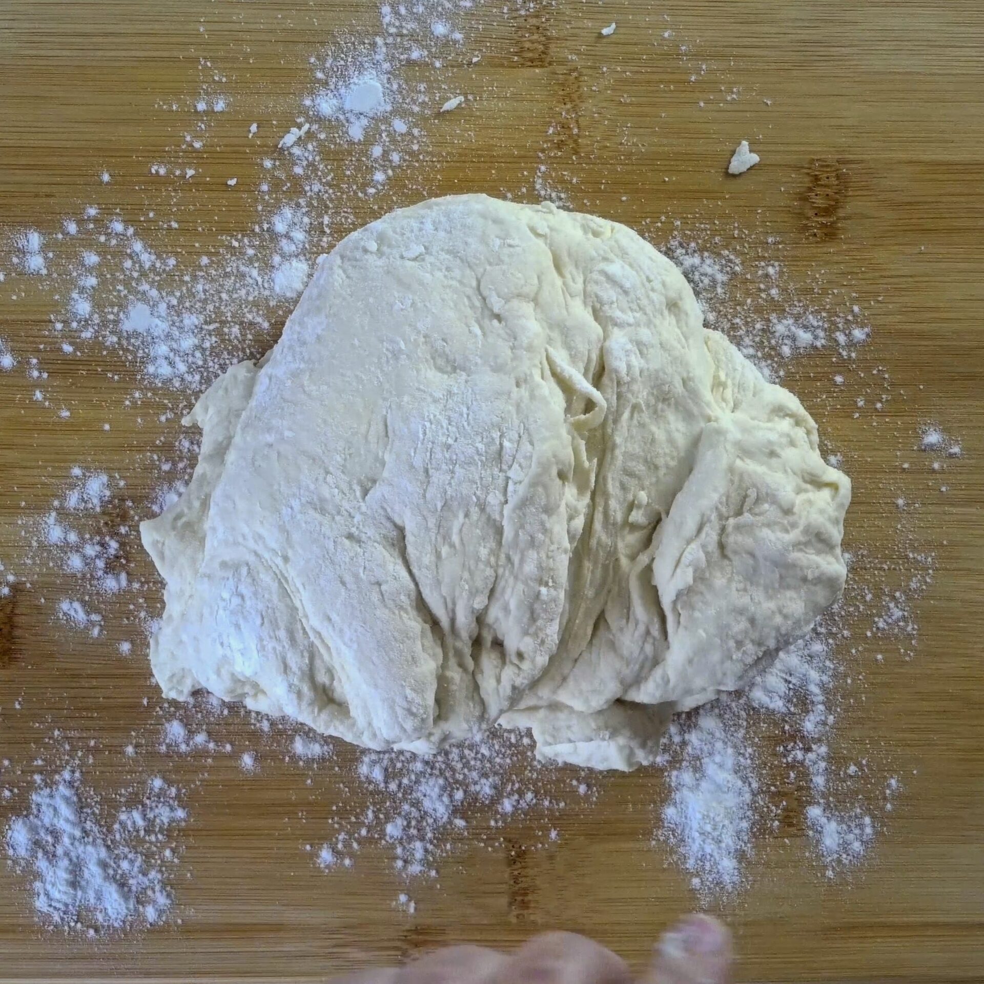 Roti dough resting on a floured surface, ready to knead.