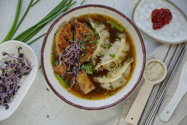 Freshly cooked gyoza soup in a bowl with delicious broth, veggies, and crispy tofu.