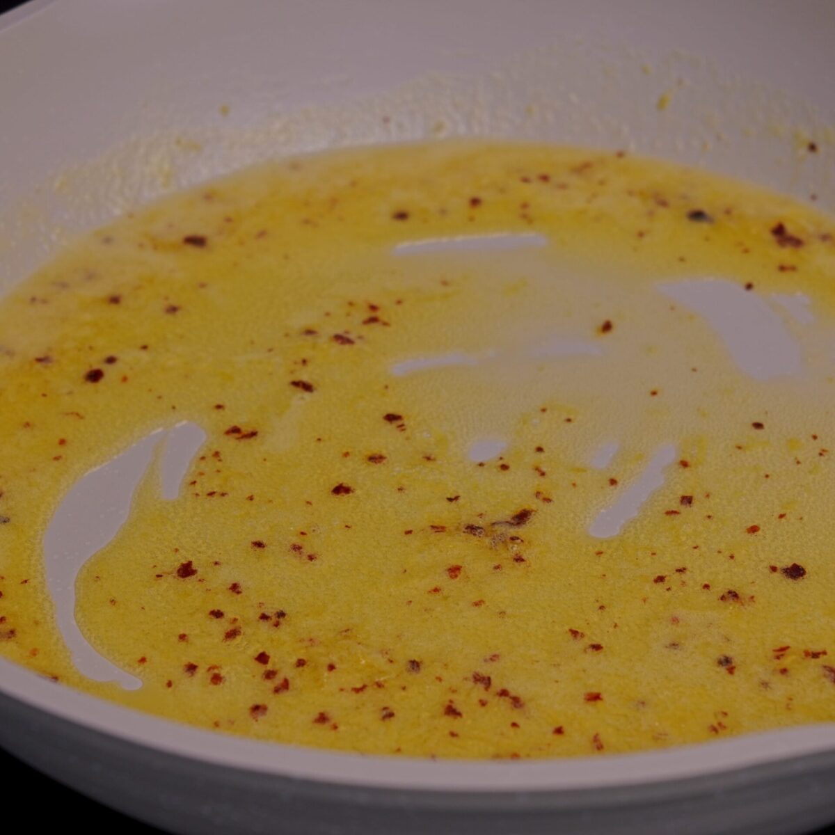 Close-up of emulsified pasta sauce in a pan, smooth and glossy.