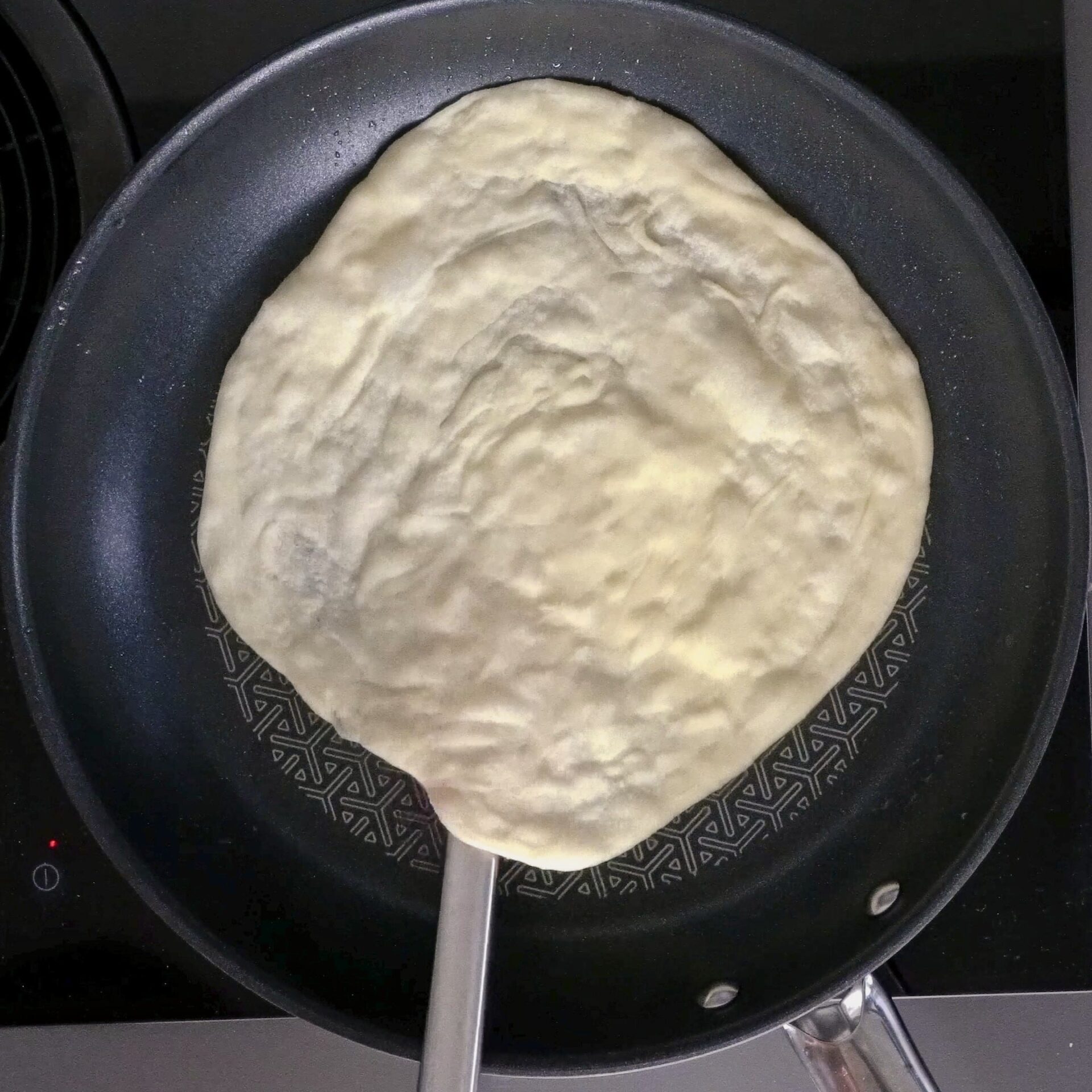 Flipping the roti to cook evenly on both sides.