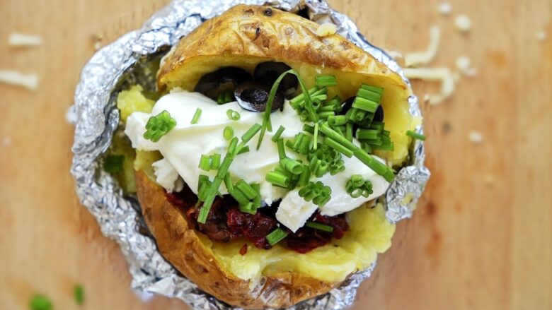 Baked potatoes with vegetarian toppings, sour cream sauce, and sprinkled onions.