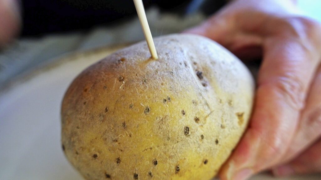 Poking potatoes with a toothpick before baking.