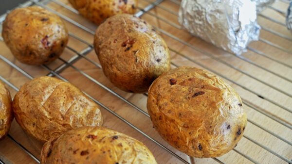 Removing baked potatoes from the oven before mashing with cheese and butter.