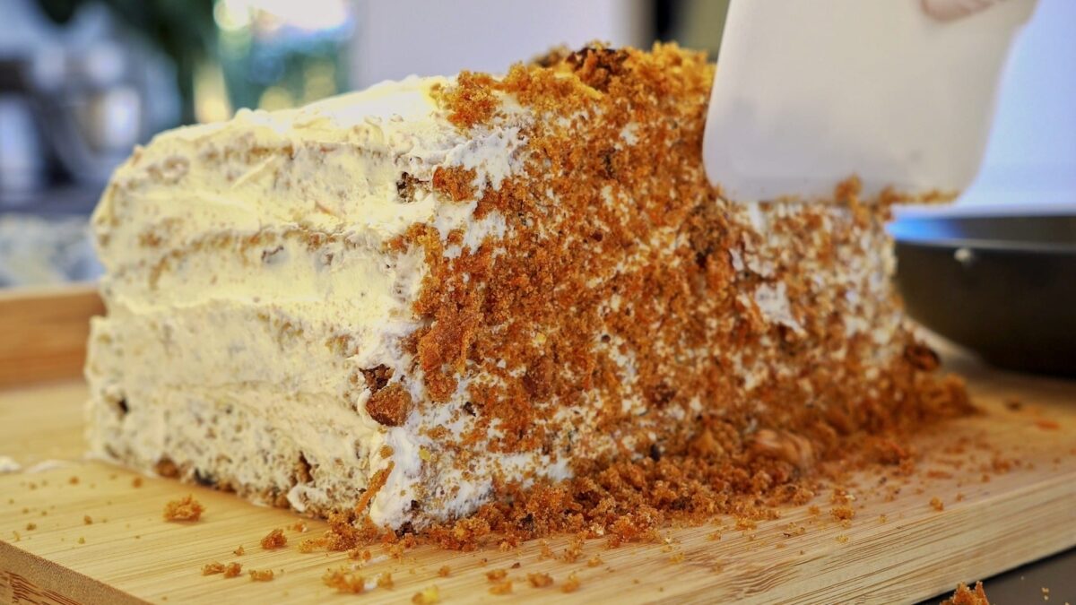 Covering the defrosted carrot cake with crumbs.