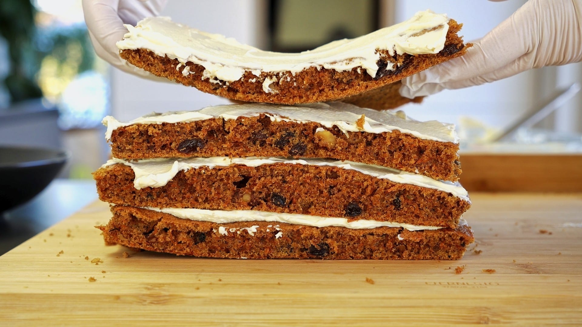 Frosting carrot cake layers with cream cheese frosting after freezing and defrosting.