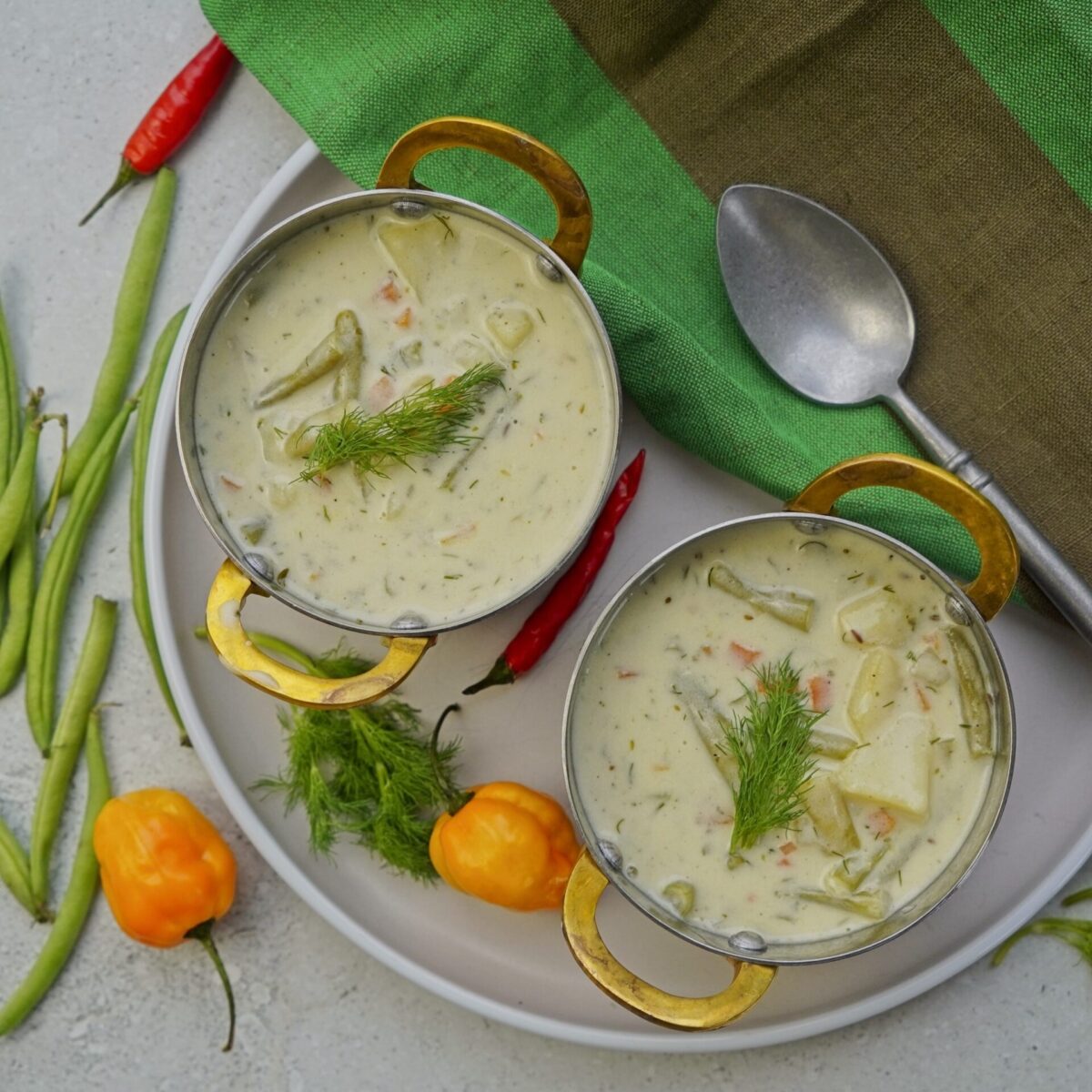 Two servings of green bean potato soup topped with fresh dill.