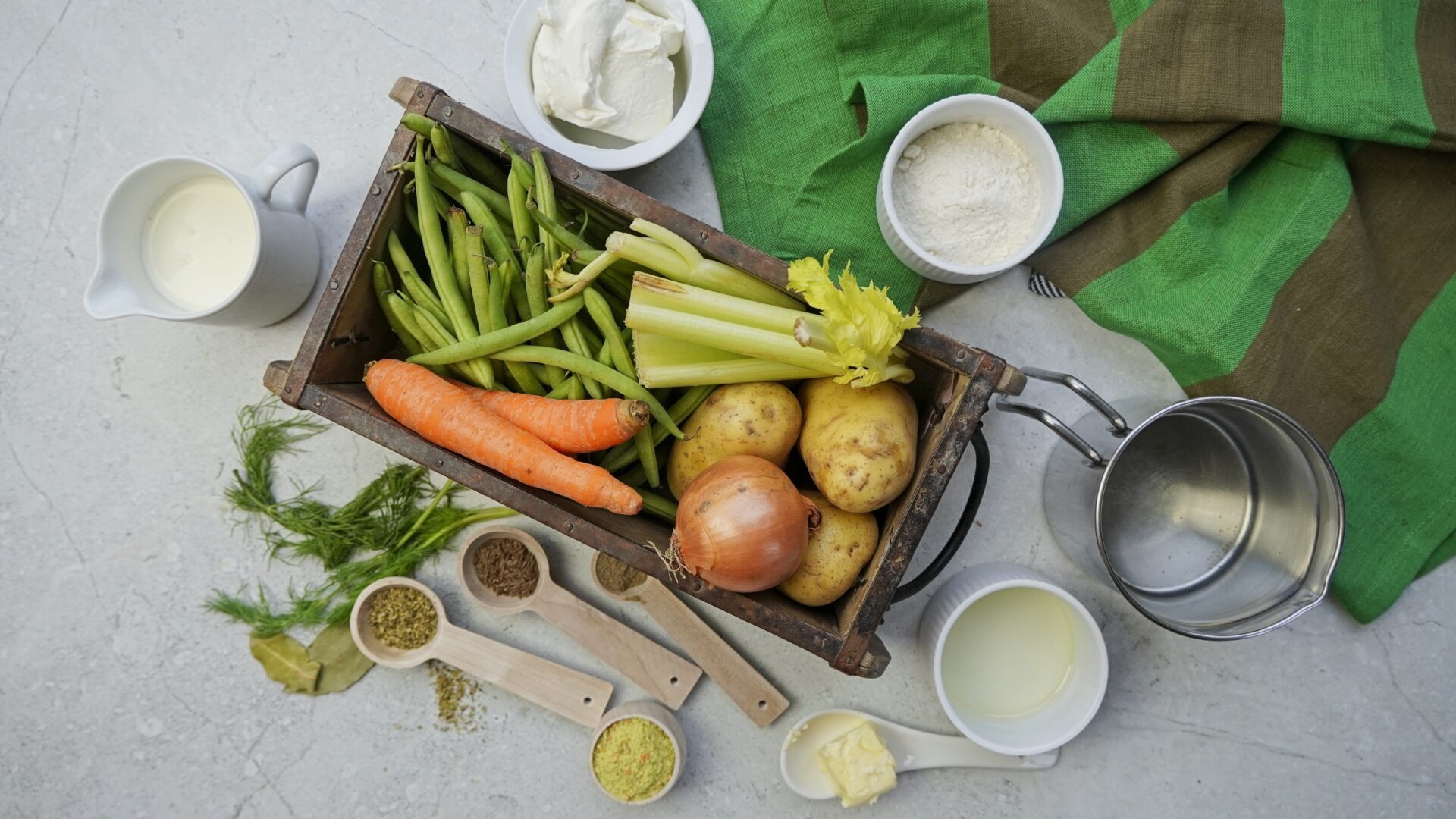 Ingredients for green bean potato soup: green beans, potatoes, onion, carrot, celery, vegetable oil, butter, vegetable stock or water with dry bouillon, oregano, whole cumin seeds, black pepper, bay leaves, sour cream, heavy cream, all-purpose flour, fresh dill, and salt to taste.