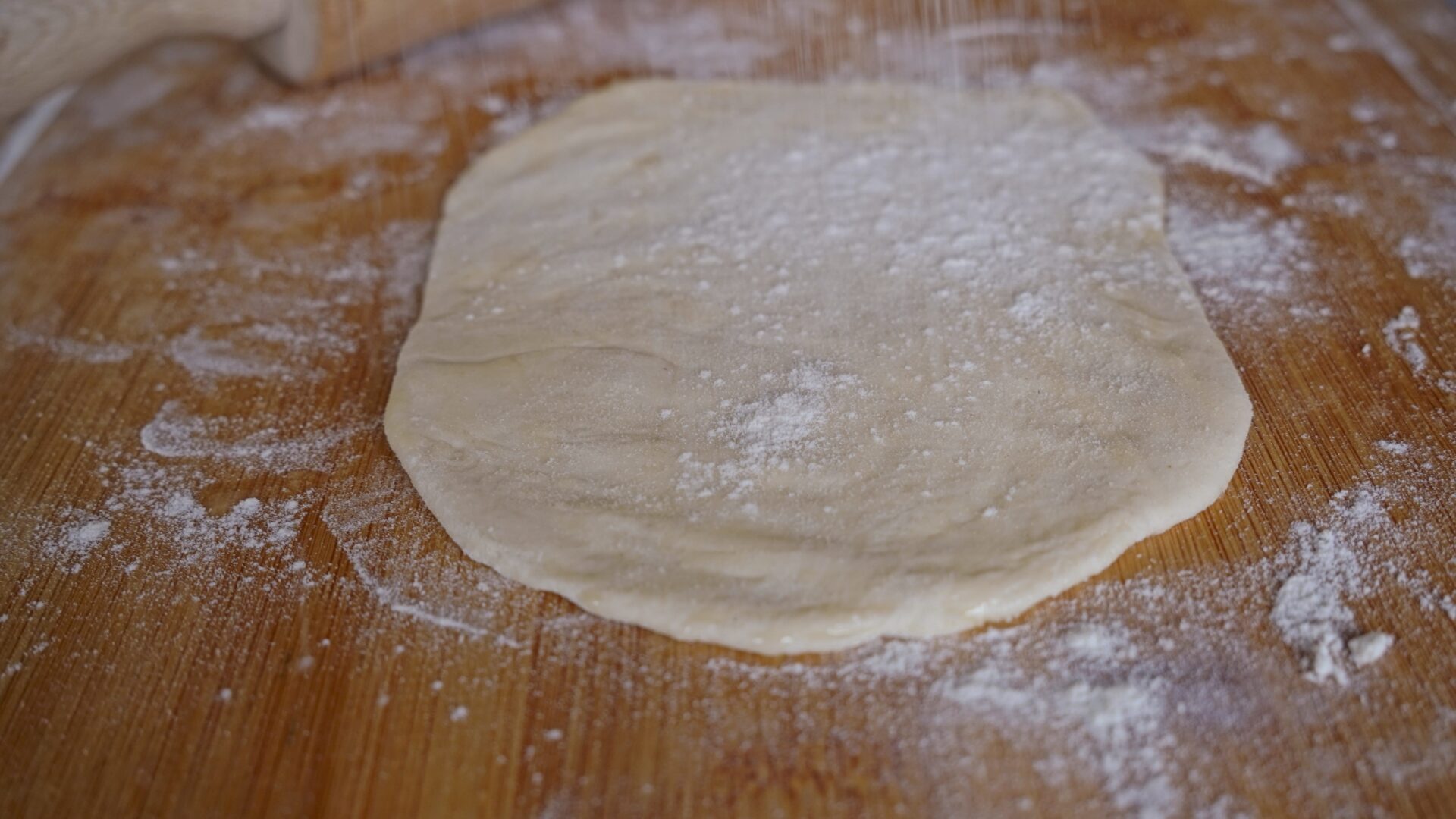Sprinkling thin roti dough with flour.