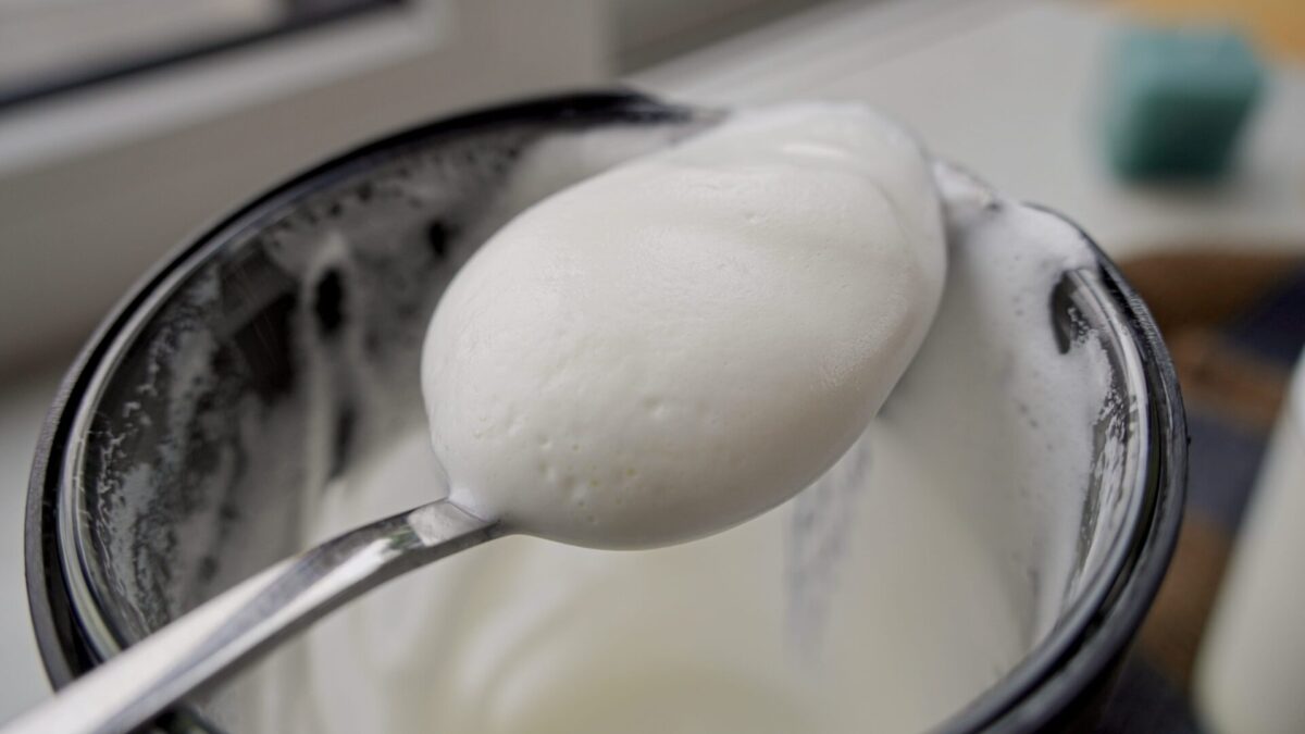 Frothed milk on a spoon, ready to top a cappuccino.