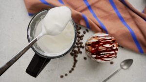 Spoonful of frothed cold milk with a delicious iced coffee on the side.
