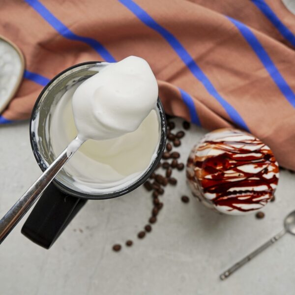 Creamy frothed milk in a spoon, photographed from directly above.