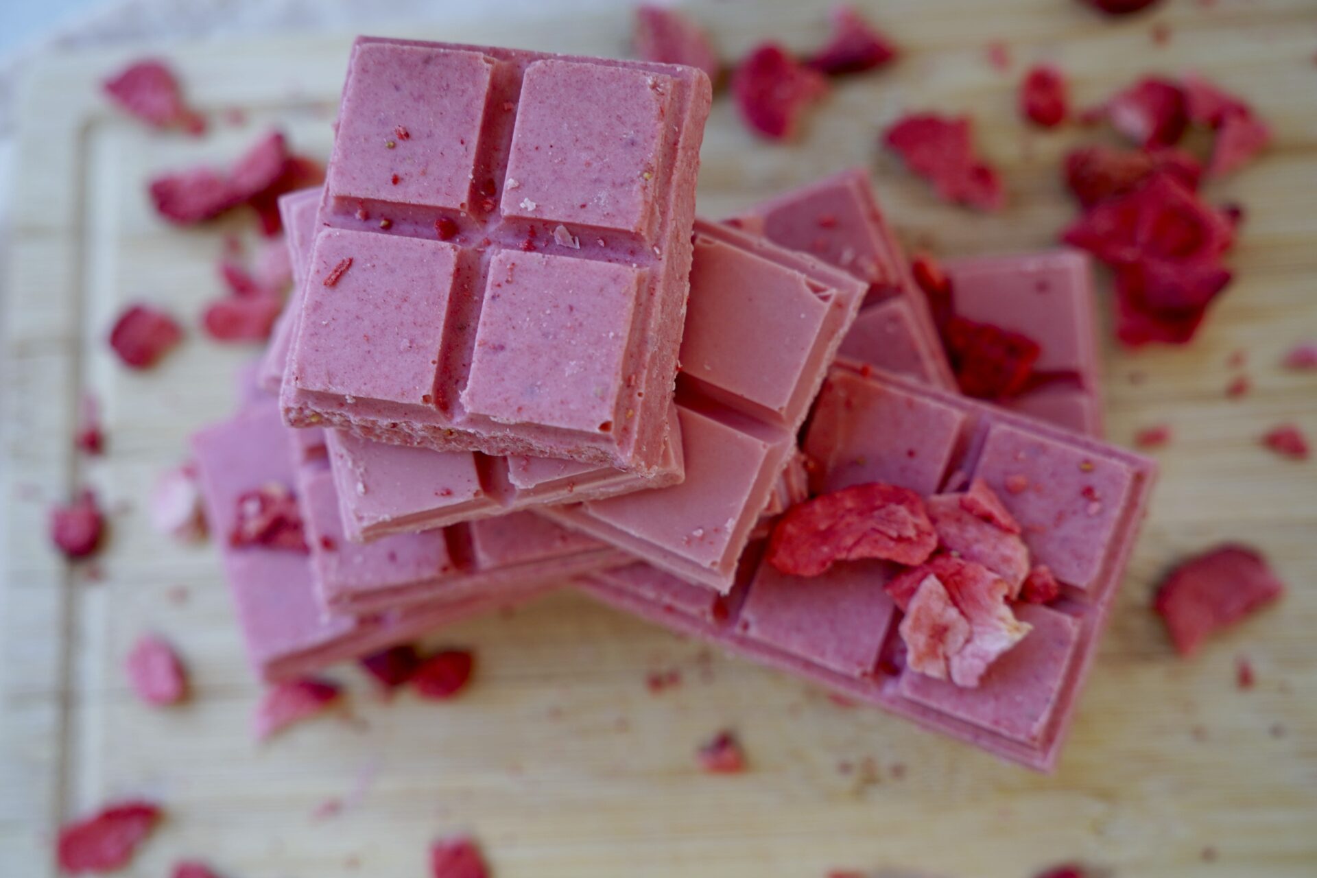 Pieces of pink chocolate decorated with dried strawberry bits.