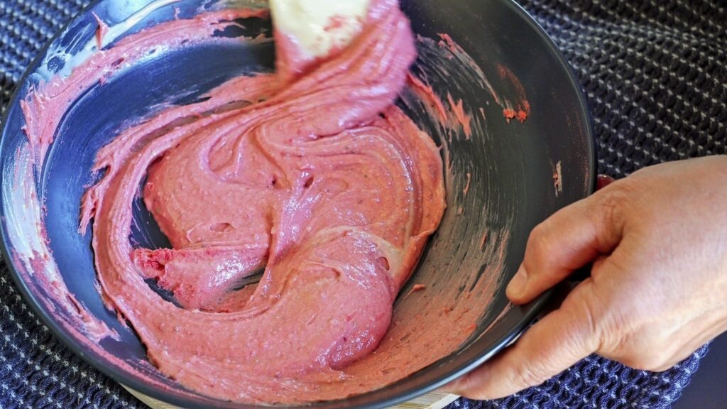 Mixing dried strawberry powder with melted white chocolate to make pink chocolate.