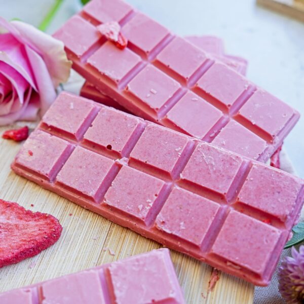 Pink chocolate made with strawberries and food coloring on a cutting board.