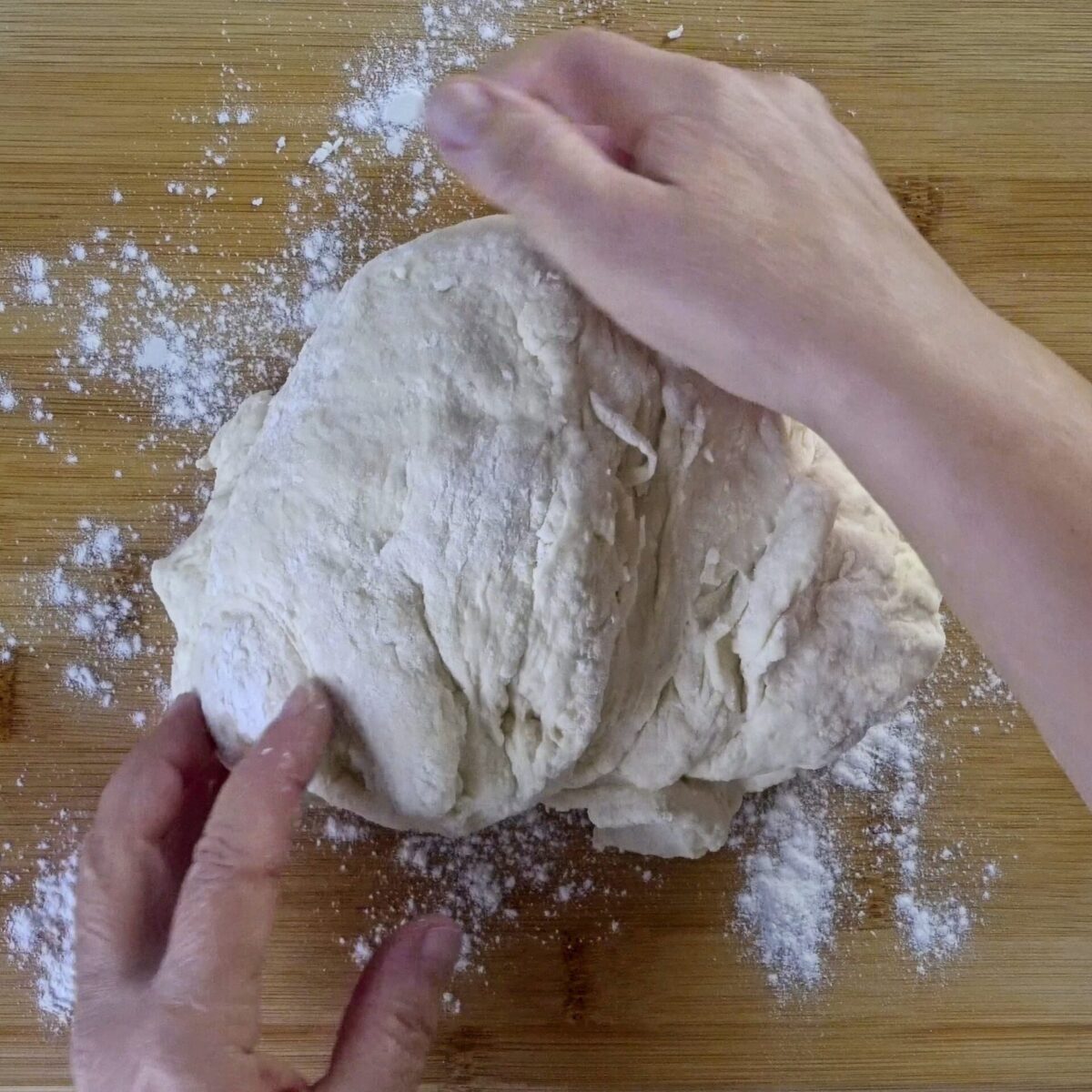 Kneading the dough until smooth, elastic, and slightly sticky.
