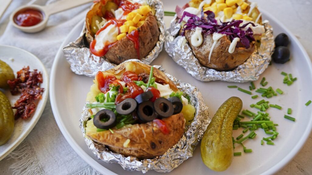 Baked potatoes with various toppings presented on a table.