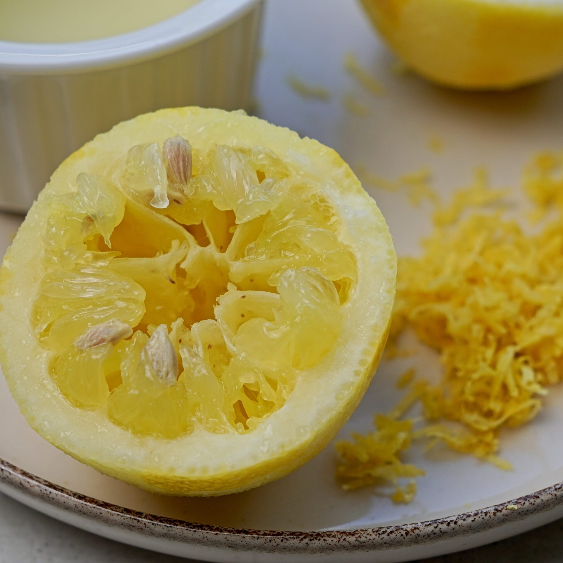 Squeezed lemon and lemon zest on a plate, ready to add to the pasta.