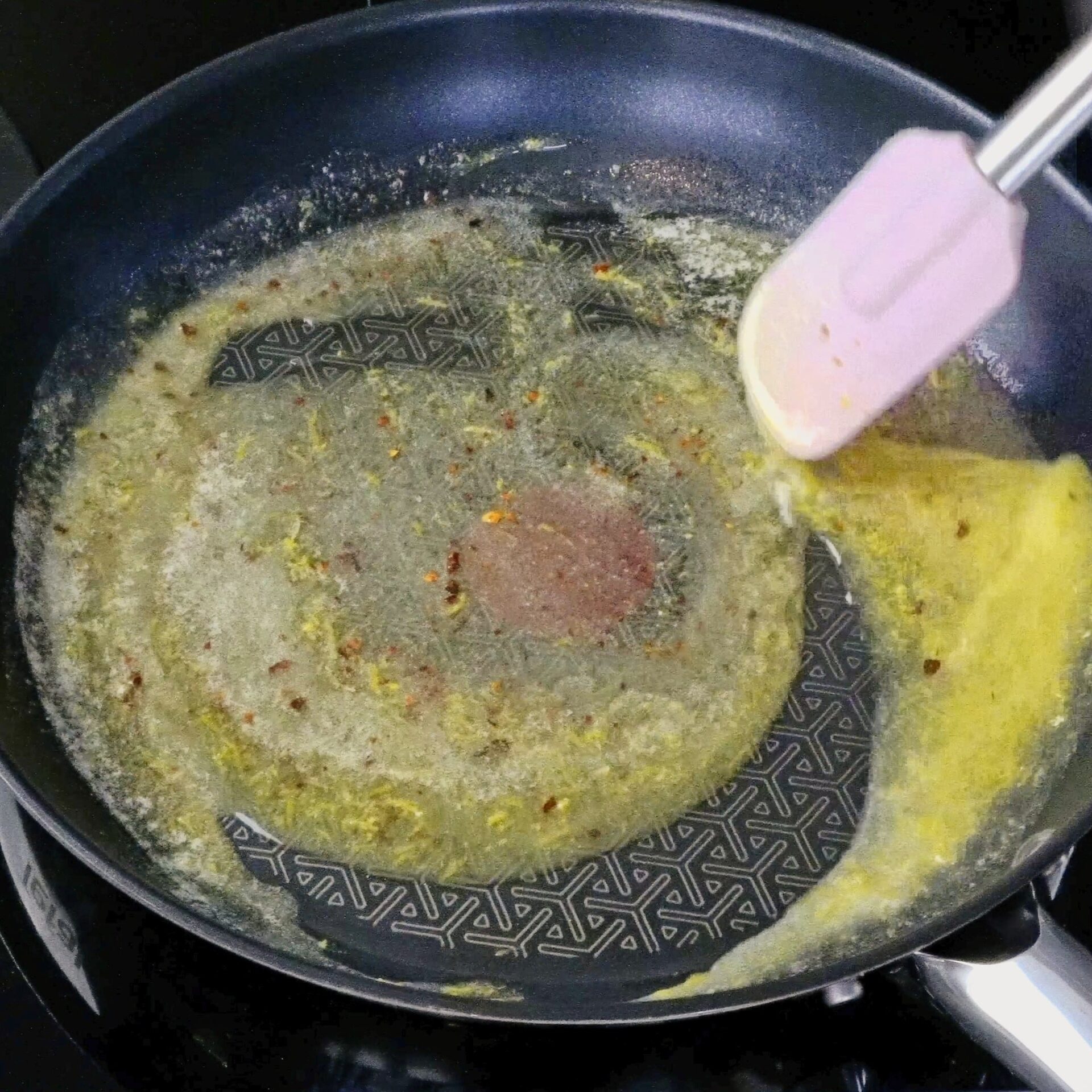 Stirring spices and lemon zest into melted butter in a pan.